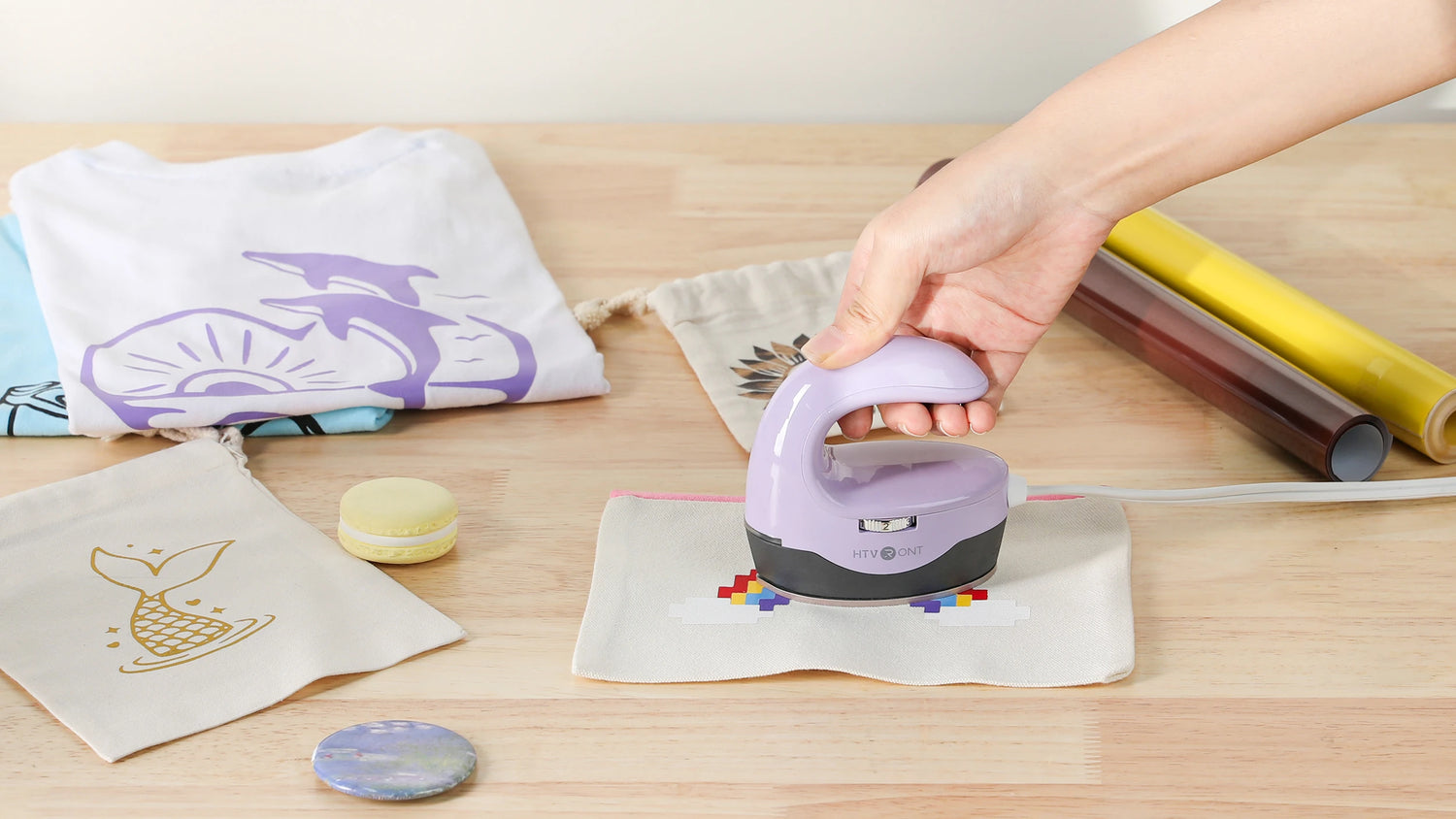 Person using a purple paper punch on a piece of paper with a wooden surface and fabric in the background.