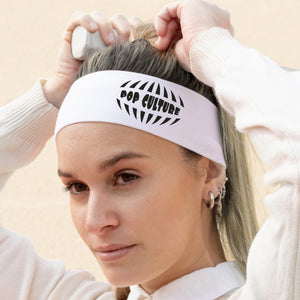 Woman wearing a white headband with 'Pop Culture' text, adjusting it on her head.