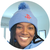 Person wearing a blue beanie with a logo, smiling indoors.